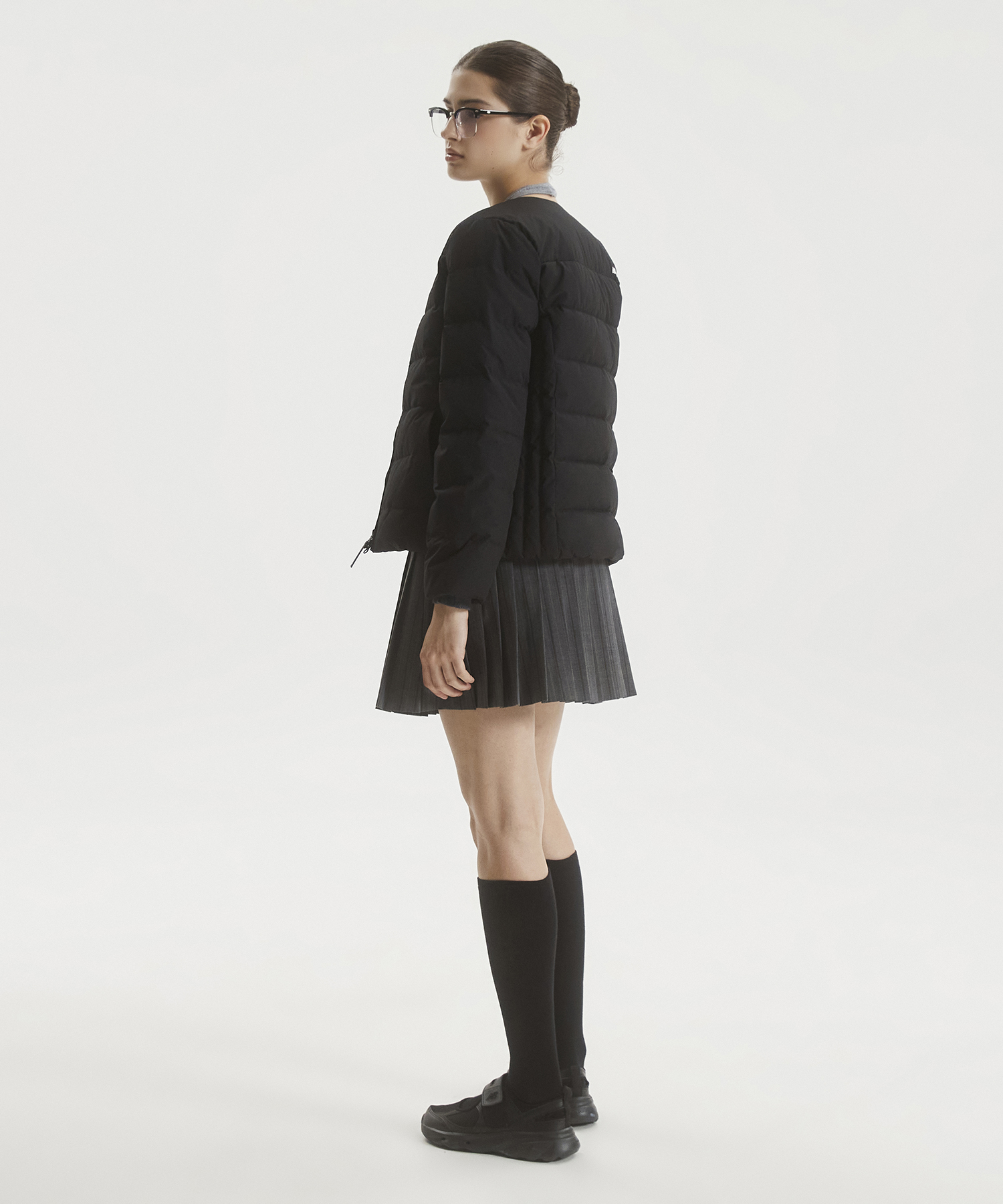 깔끔한 블랙 컬러의 뉴발란스 액티브 라이트 다운이 침대 위에 가볍게 놓여 있는 모습