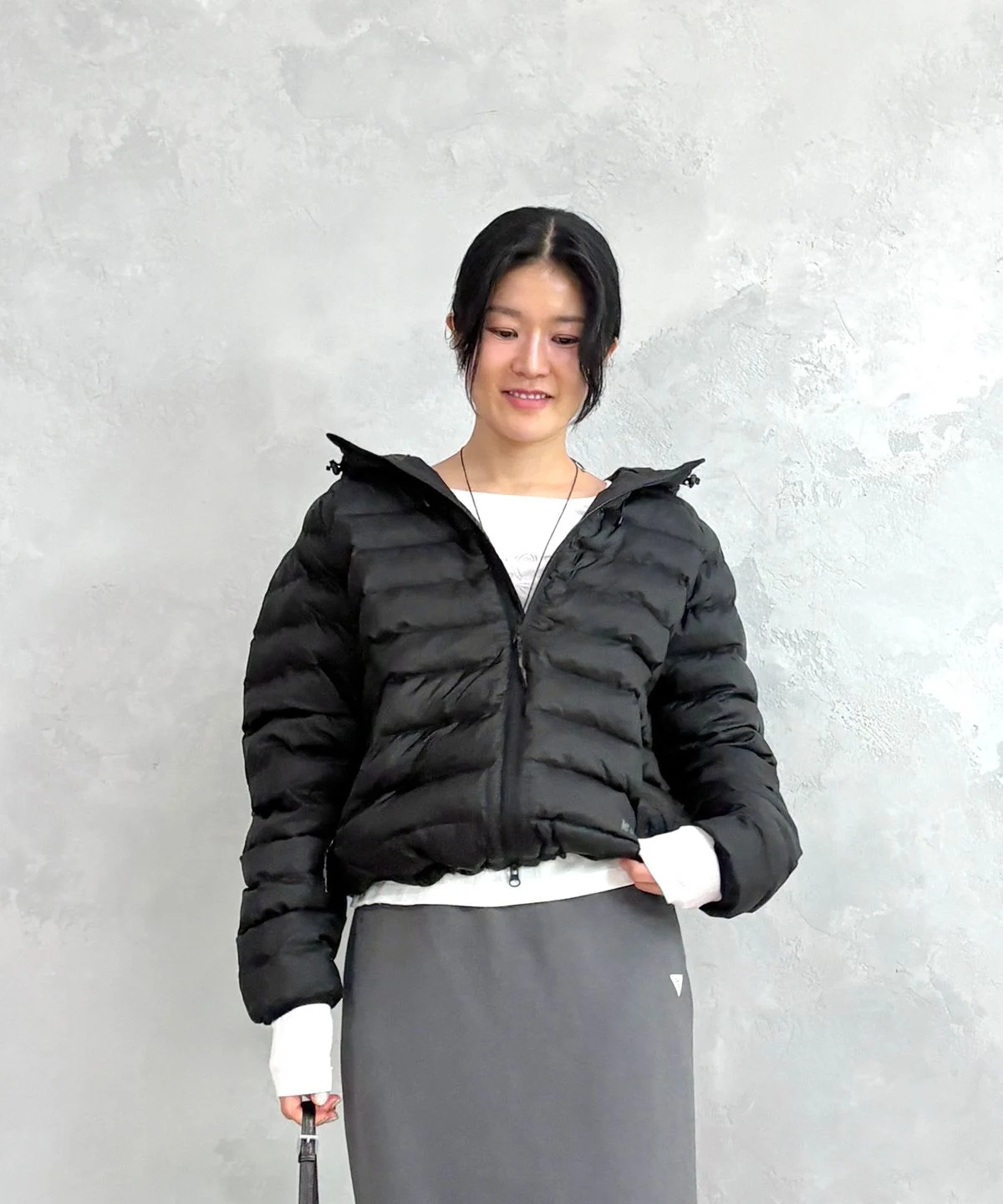 묵직한 겨울 패딩 사이에서 가벼운 르꼬끄 경량 볼패딩을 한 손으로 가볍게 들고 있는 모습